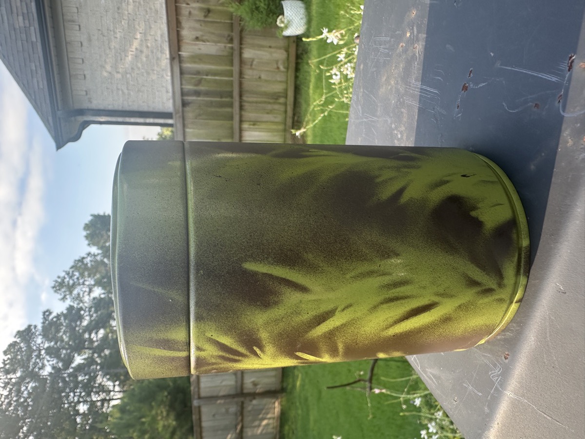 The Can: a green coffee can wearing hand-sprayed leaf camouflage